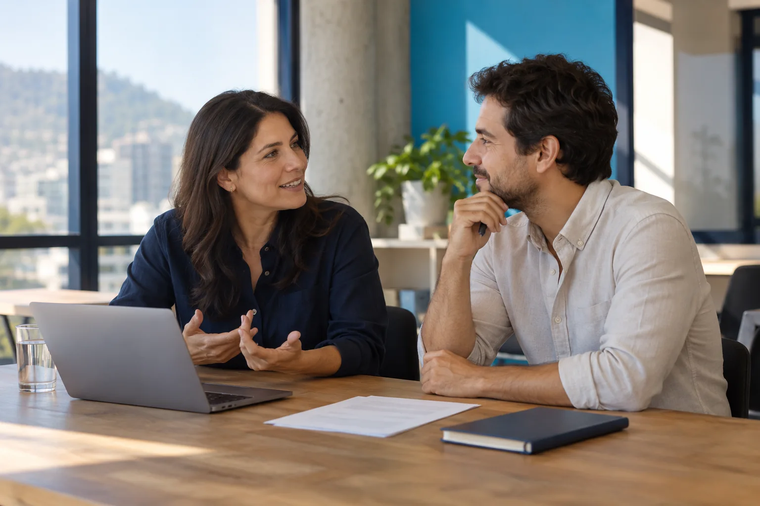 Imagen conceptual de dos profesionales colaborando en una mesa de trabajo.